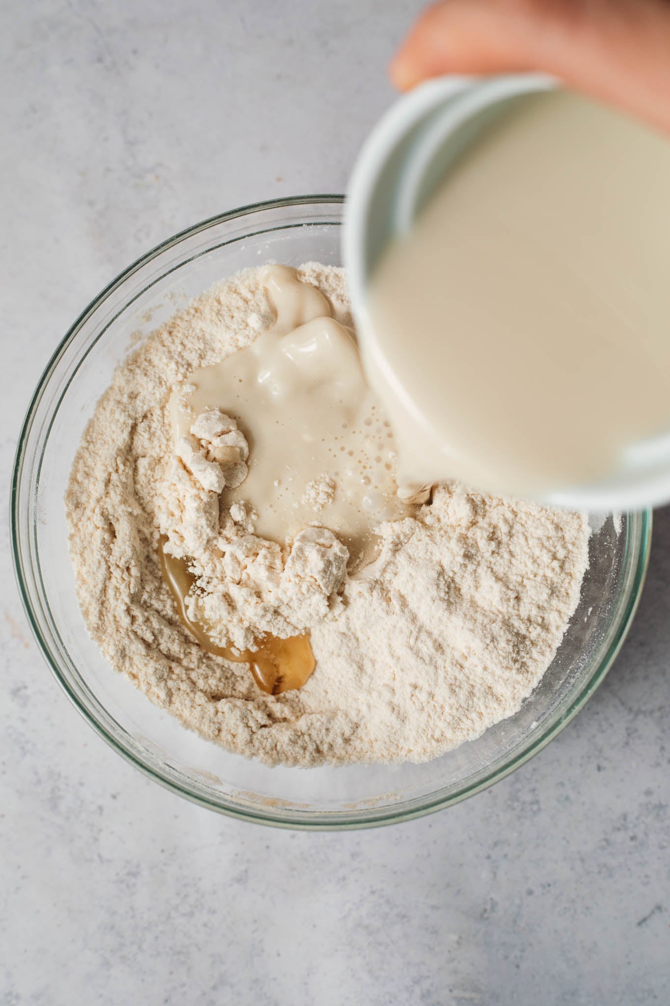 overhead shot of plant milk pouring into dry ingredients mixture for buttermilk pancakes