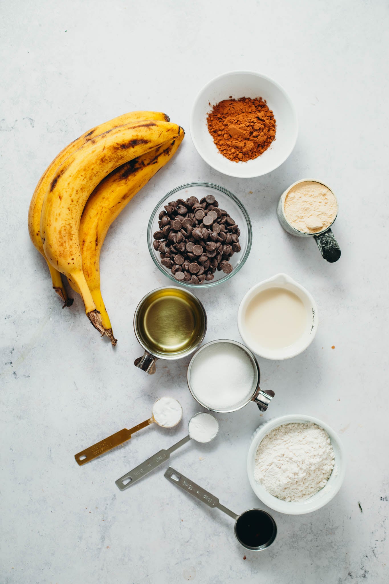 overhead view of ingredients for chocolate banana bread on a white background