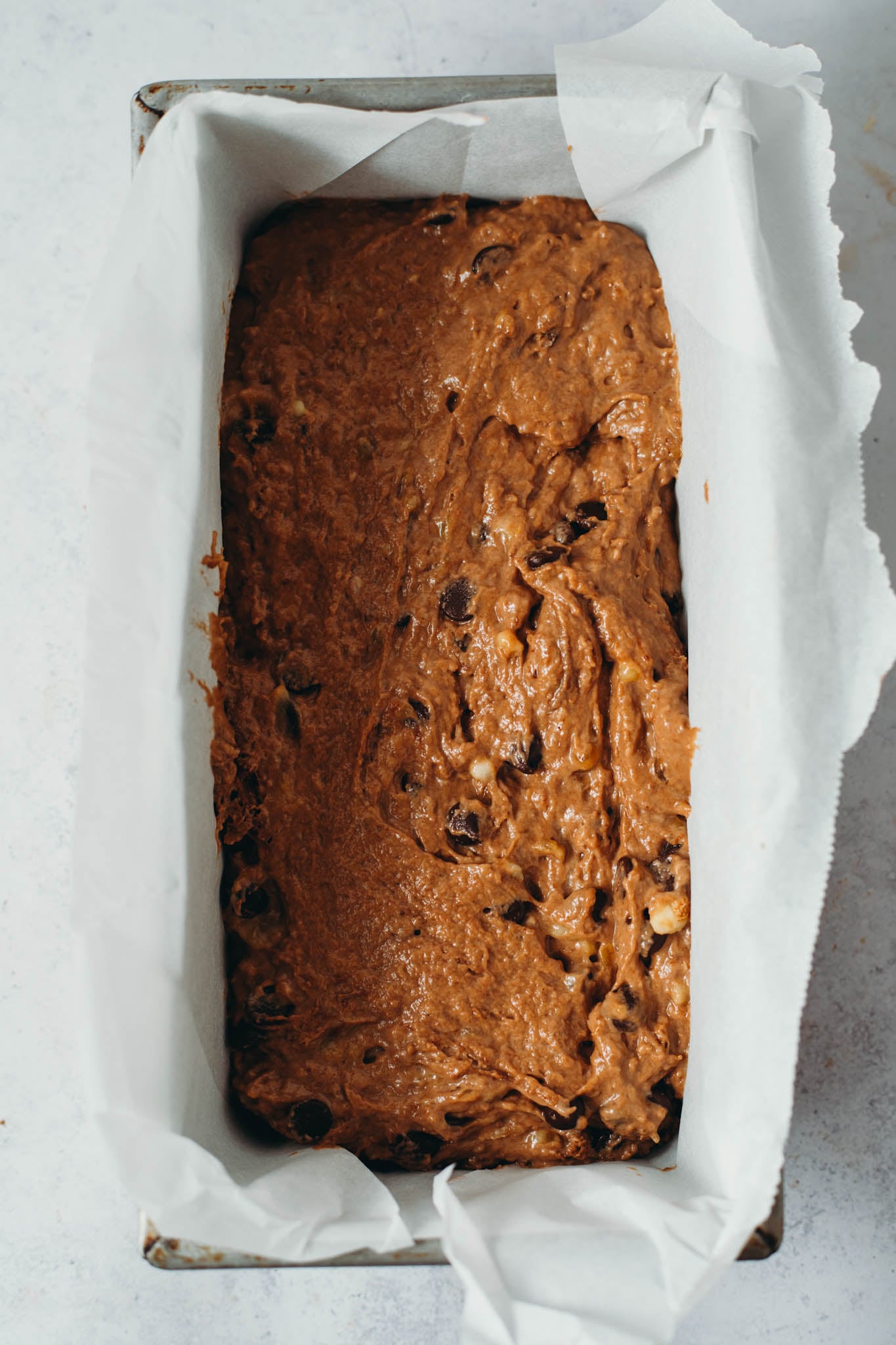 overhead view of vegan chocolate banana bread spread into a long rectangle baking dish before baking.