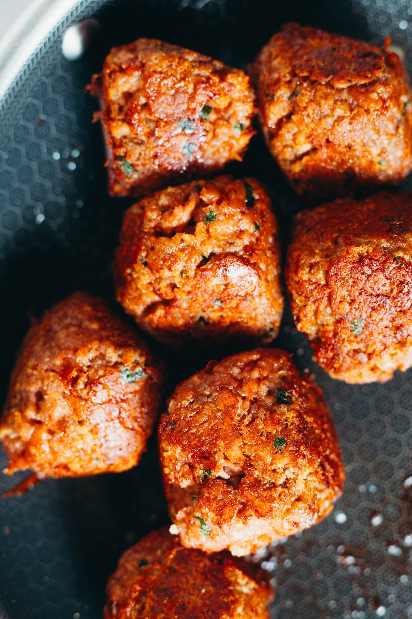Photo of meatballs being fried in a pan.