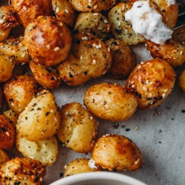 food photography of air fryer roasted potatoes dipped in a dill cream cheese sauce and sprinkled with savoury everything bagel seasoning