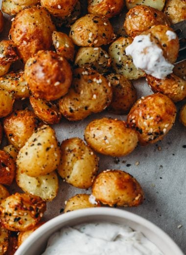food photography of air fryer roasted potatoes dipped in a dill cream cheese sauce and sprinkled with savoury everything bagel seasoning