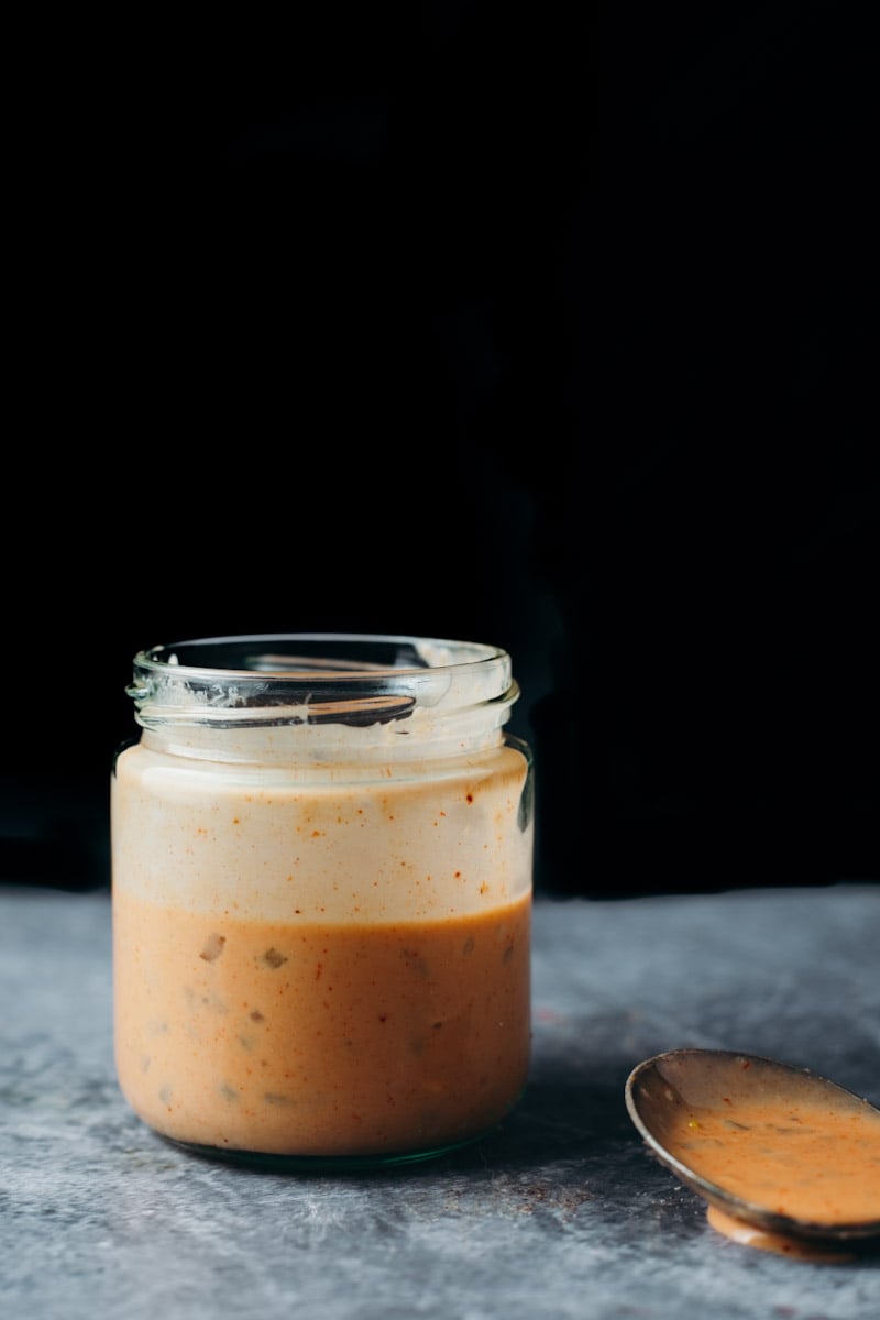 front view of vegan creamy Big Mac sauce in a class jar displaying chunks of fresh pickle