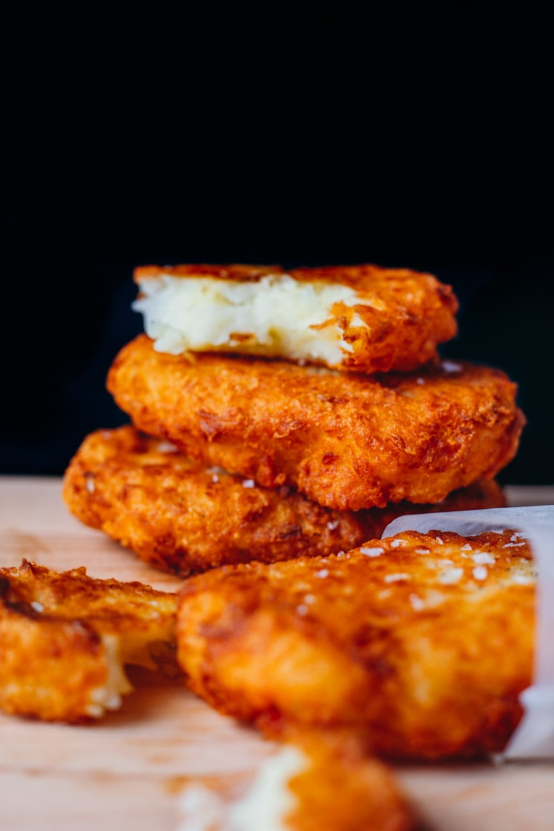 salted and deep fried McDonald's Hashbrowns Stacked on top of each other against a black back drop