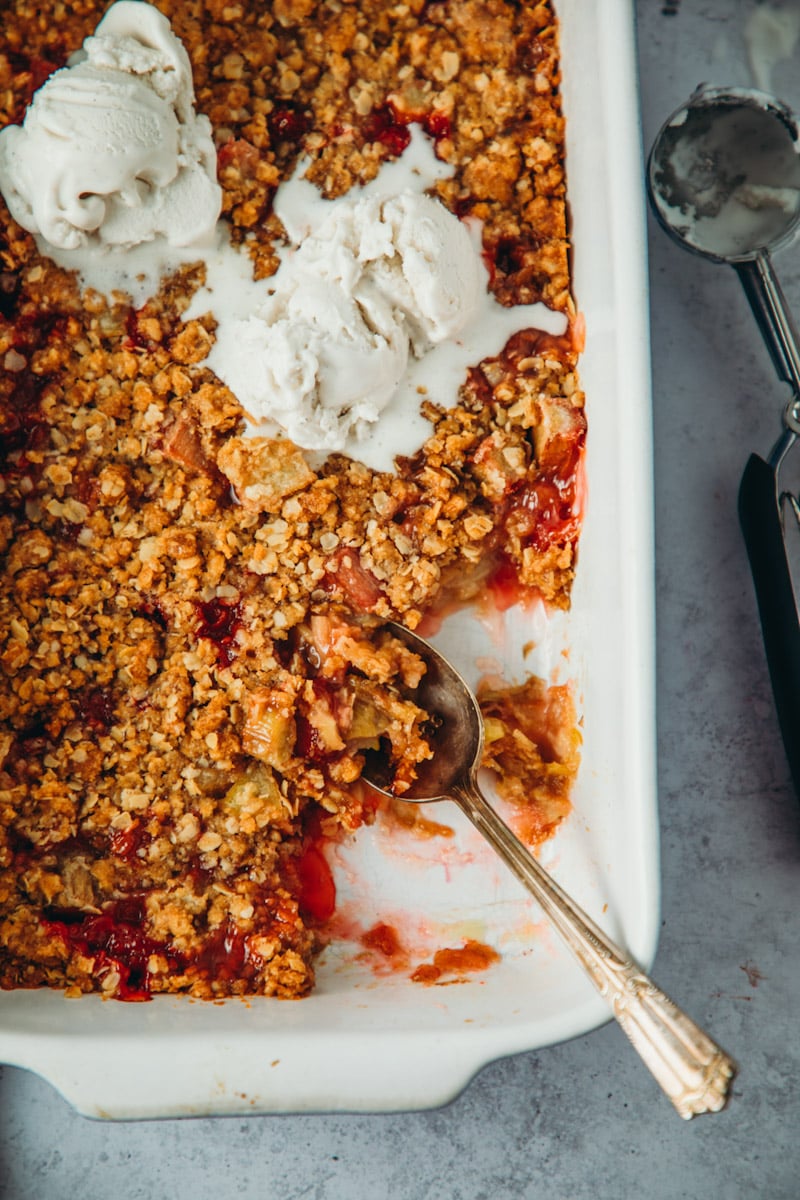 overhead shot of vegan strawberry rhubarb crisp with scoops of vanilla ice cream