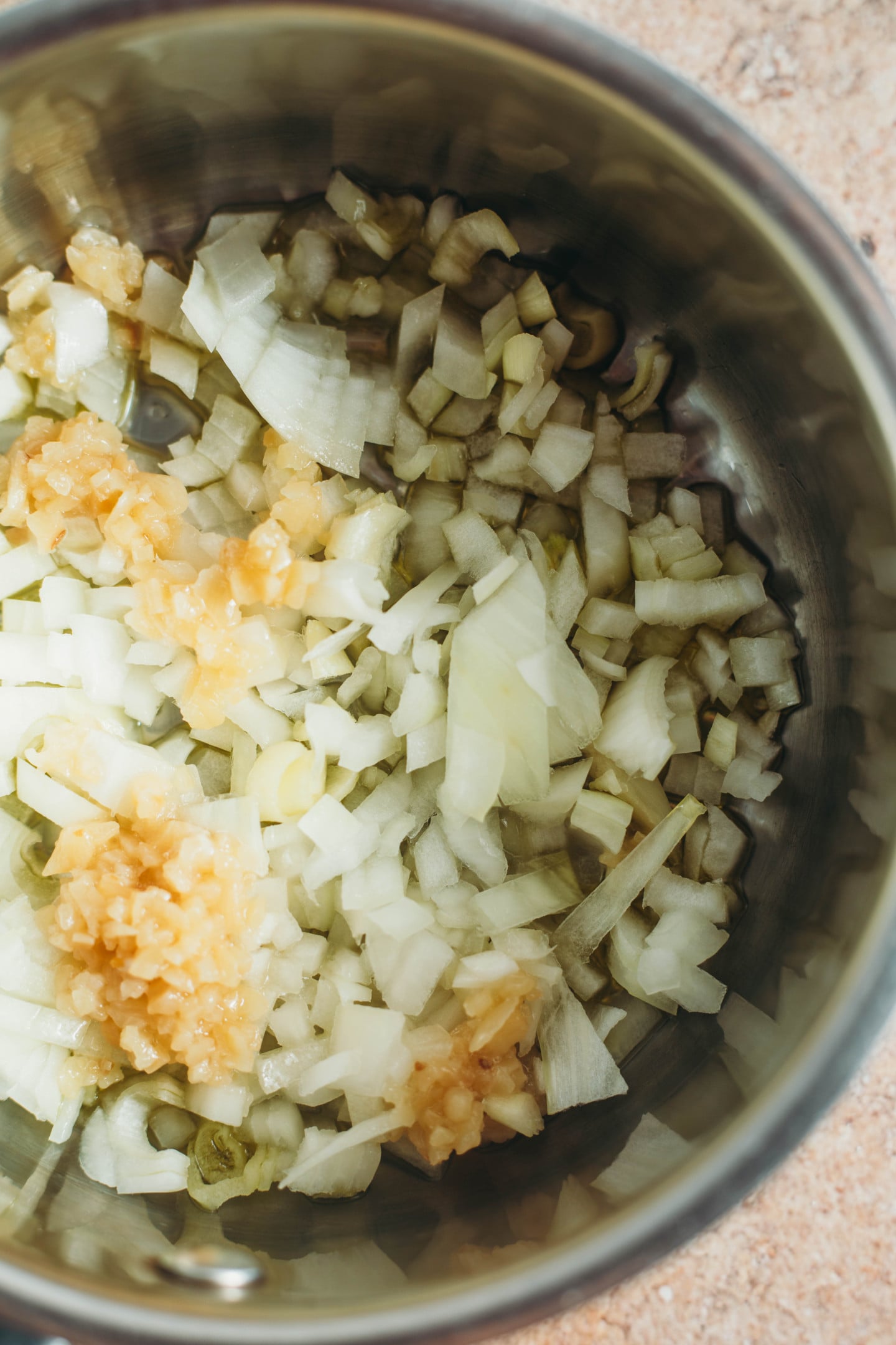 overhead view of onions and garlic being cooked in a pot.