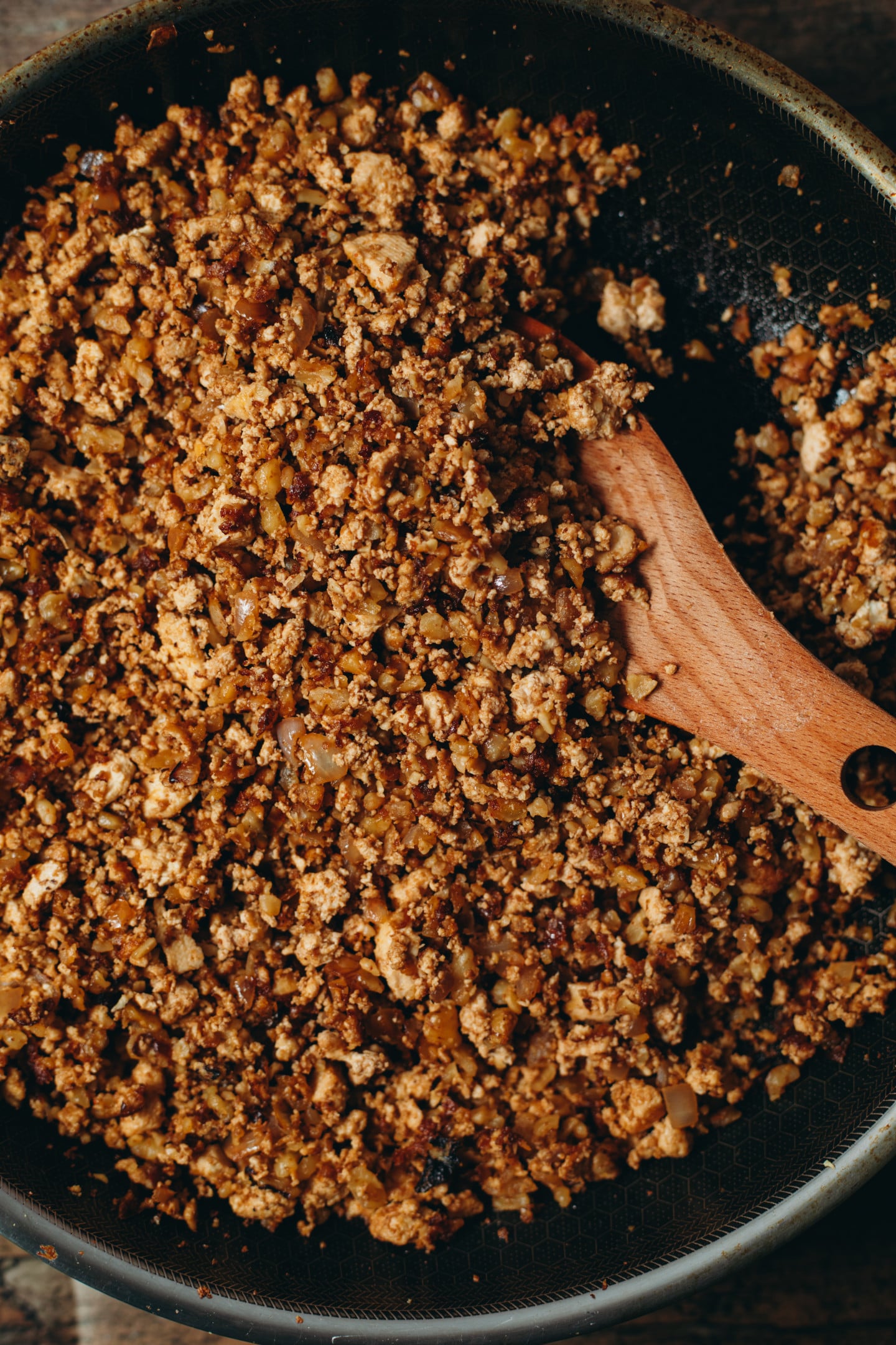 Overhead view of a spoon stirring the taco beef in a black pan.