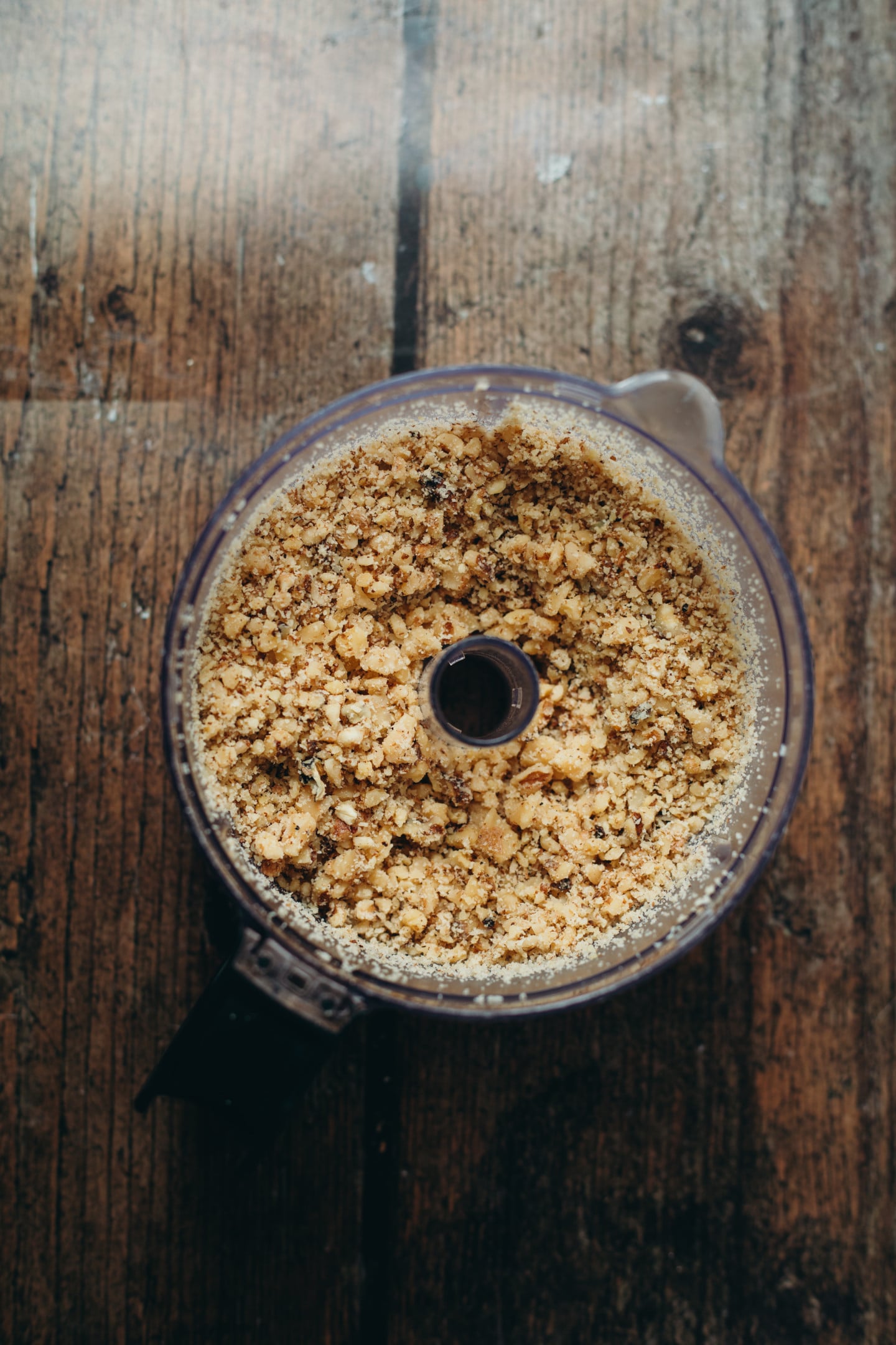 overhead view of walnuts crushed in a food processor on a wooden background.