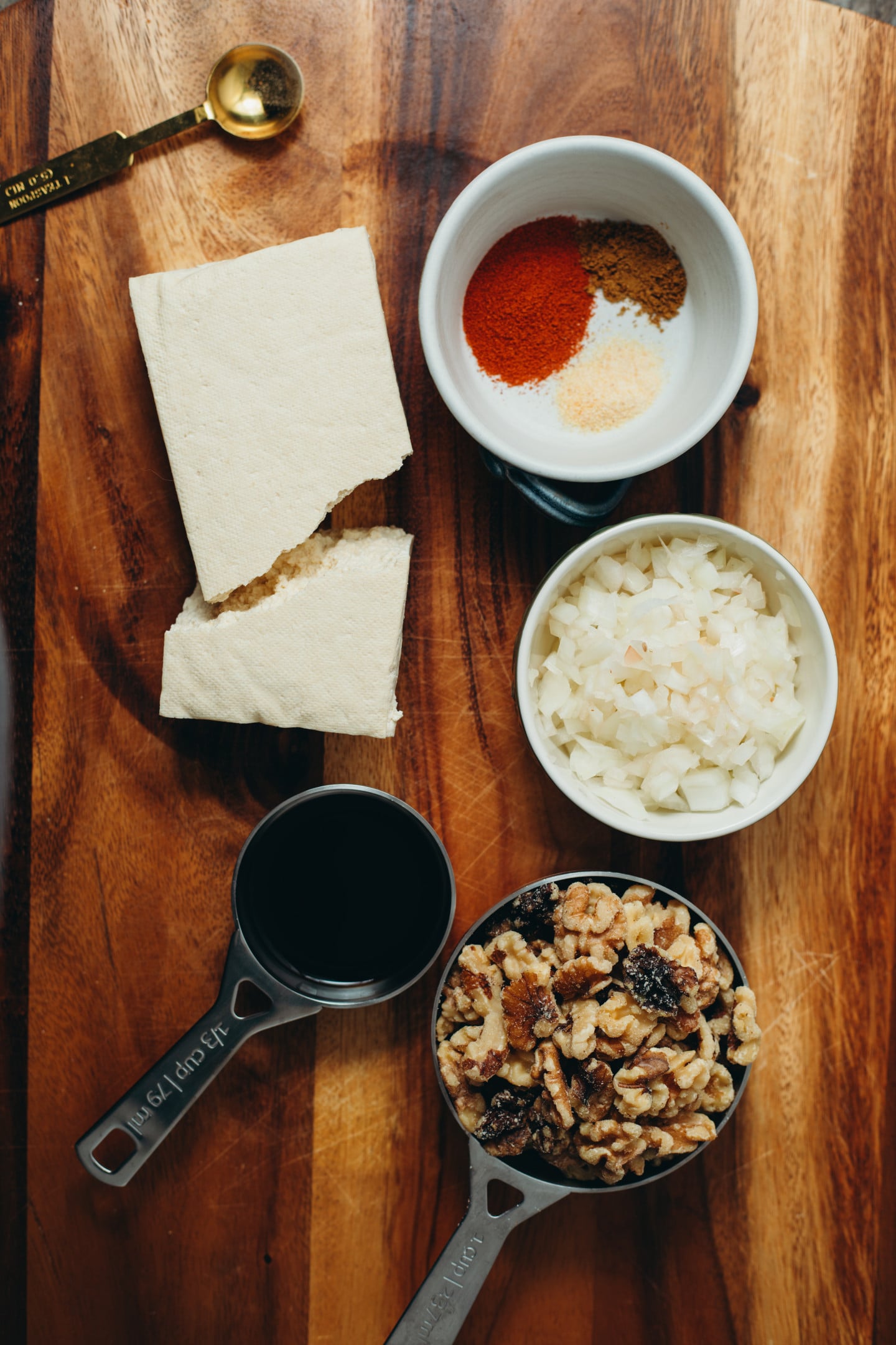 overhead view of the ingredients measured in bowls with tofu on a brown wooden background.
